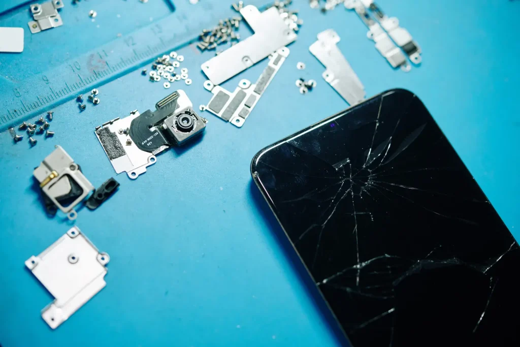 Cracked smartphone screen on a repair mat with phone parts